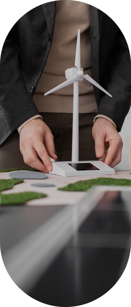 Osoba trzymająca model turbiny wiatrowej – symbol zrównoważonego rozwoju i raportowania ESG