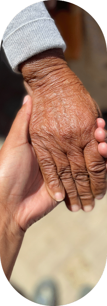 Dłonie osoby starszej i opiekuna symbolizujące wsparcie i zaufanie w opiece.